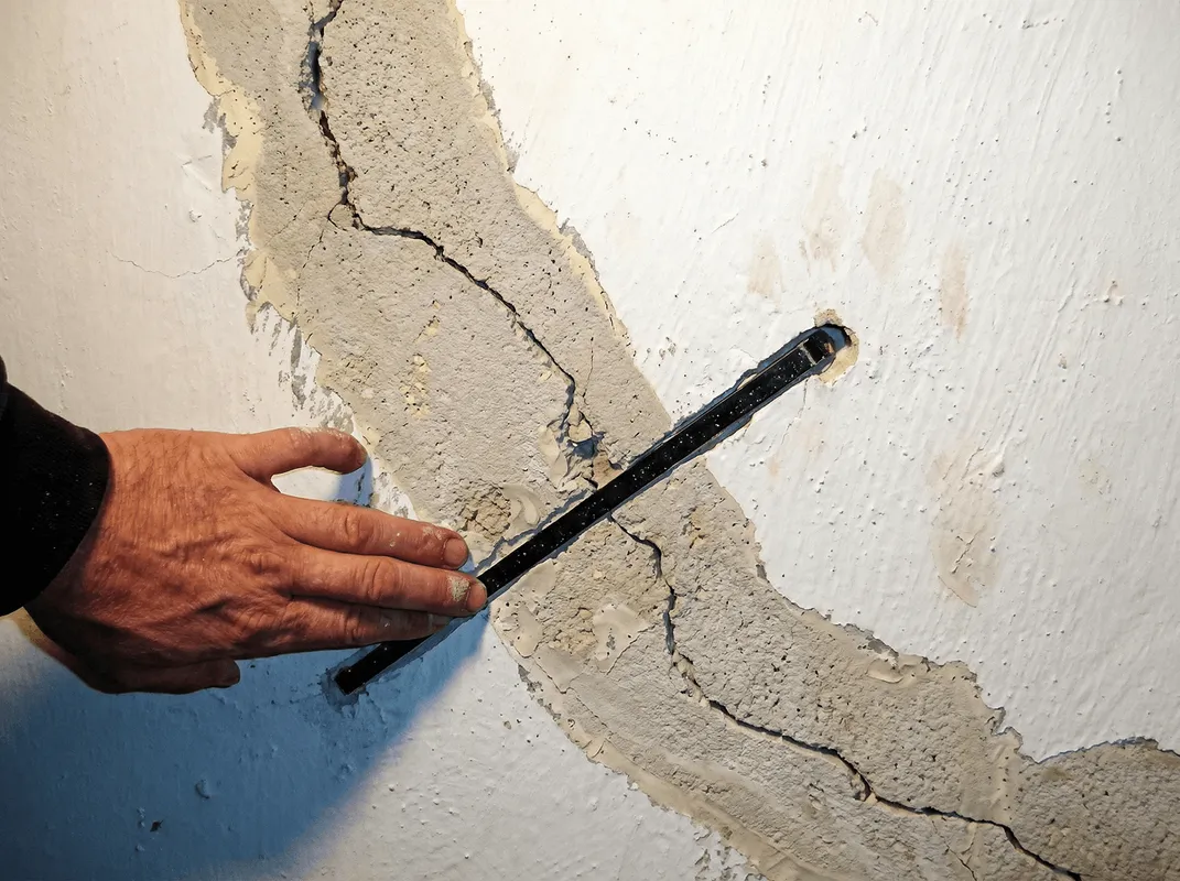 A wall with a large crack is being inspected by a professional in Glendale, AZ